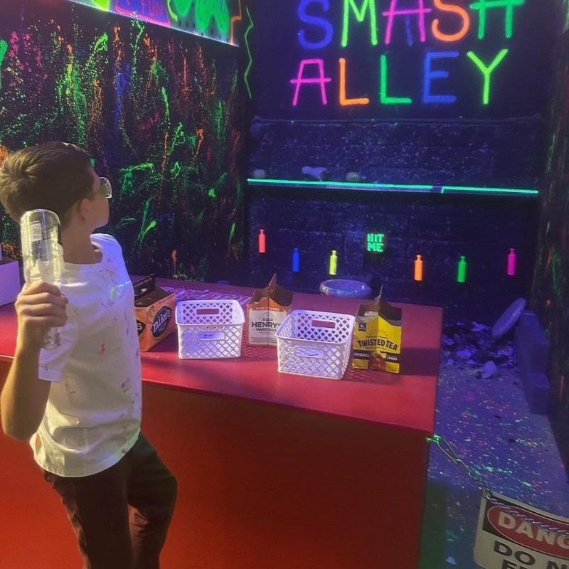 a young boy about to smash a bottle against the wall in smash alley at chaos factory