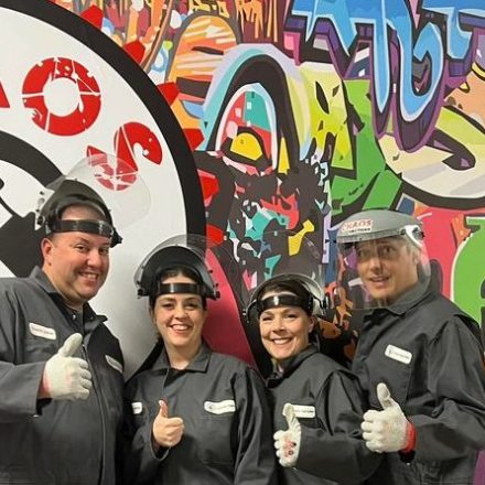 a group of people standing in front of a graffiti covered wall at chaos factory