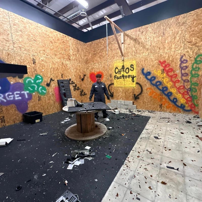 a man standing inside of the rage room at chaos factory