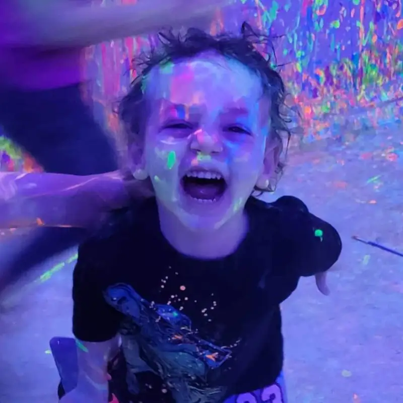 a toddler smiling big with paint all over their face
