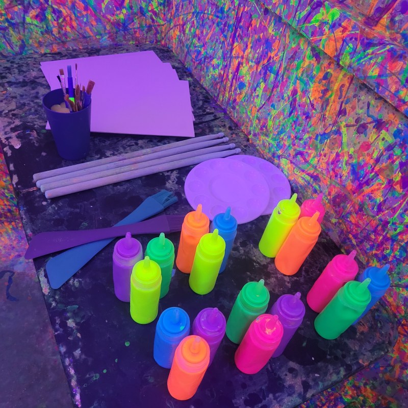 a table with paint, pallets, paint brushes and canvases at chaos factory