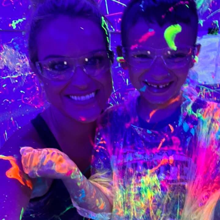 a mom and son with neon paint all over them in the splatter room