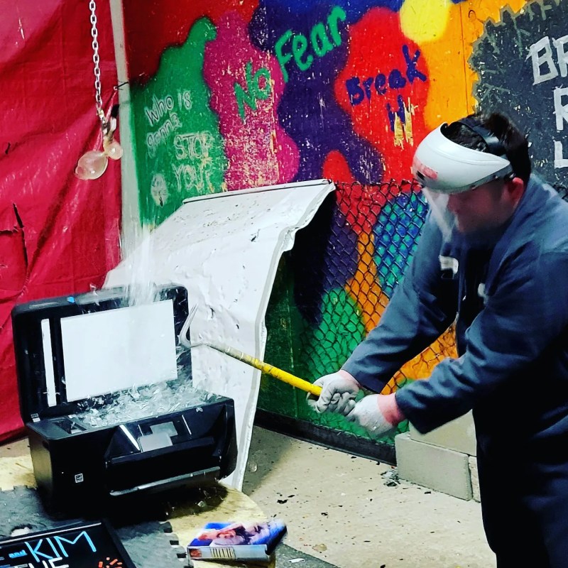 a man destroying a printer in the rage room