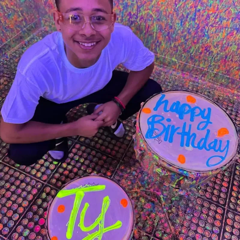 a young man kneeling next to a drum set with happy birthday Ty written on it