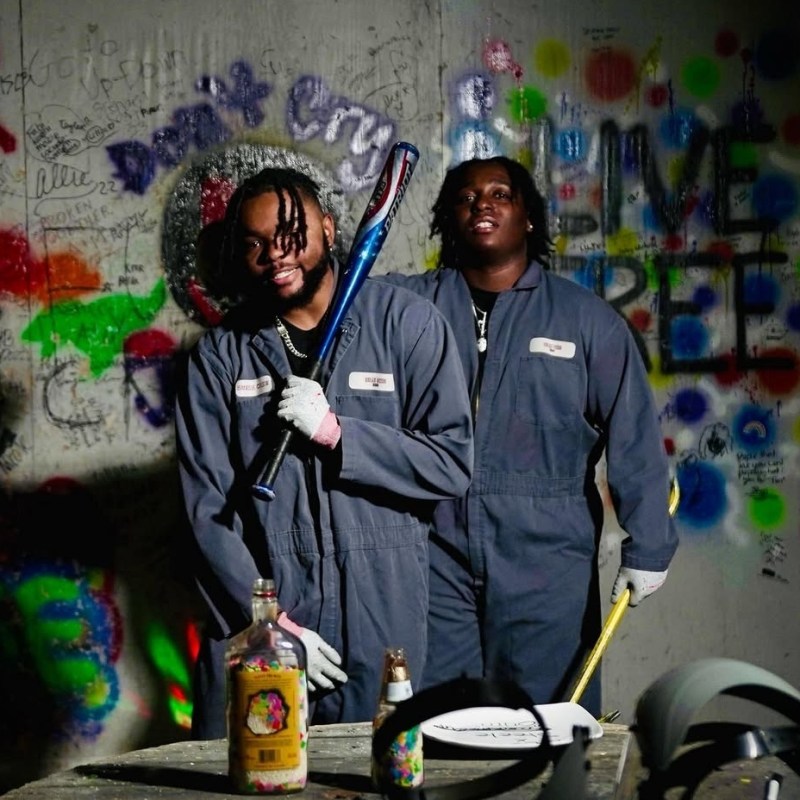 two men in coveralls smiling in the rage room
