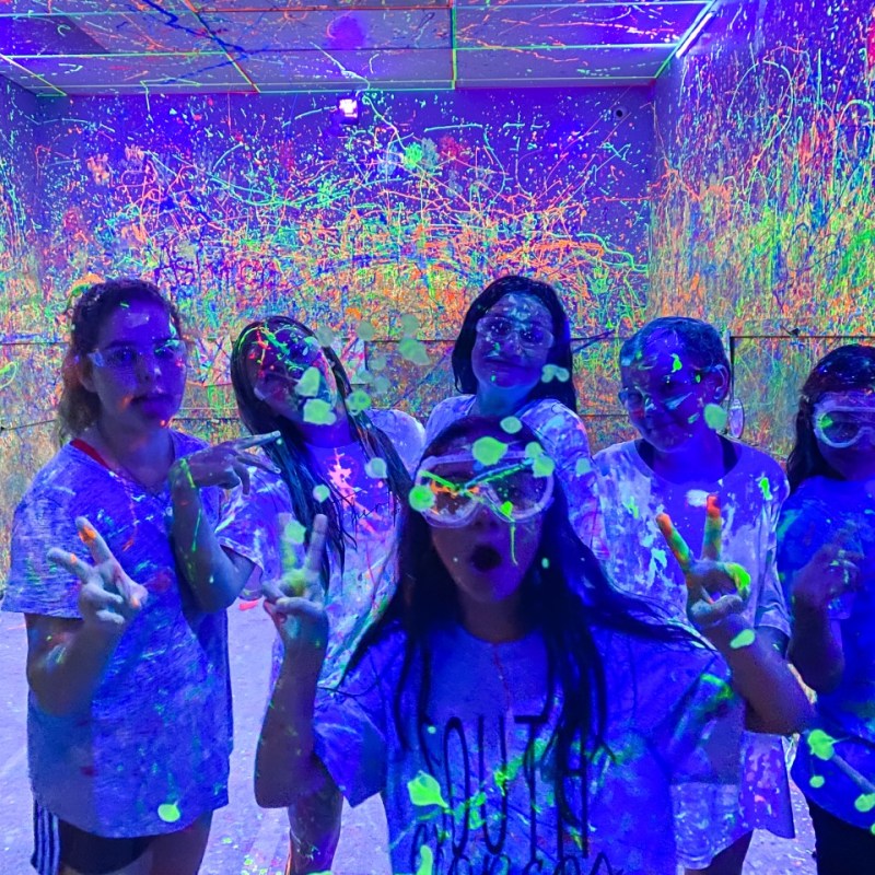 a group of girls posing inside of the splatter paint room