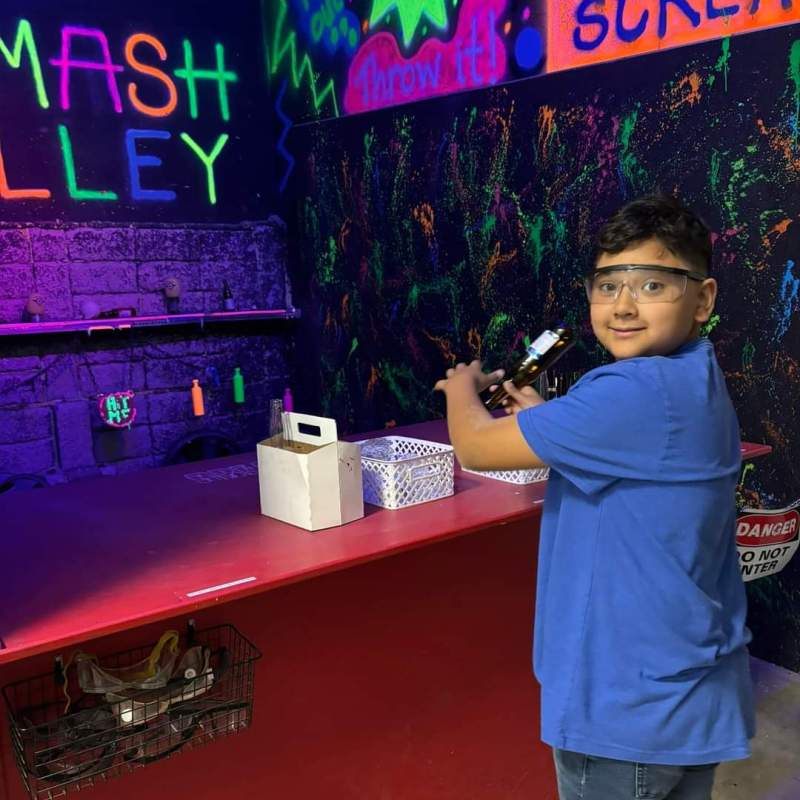 a boy standing in front of smash alley at chaos factory
