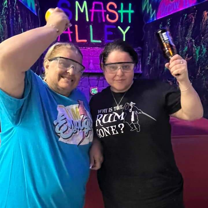 two ladies holding empty beer bottles ready to participate in smash alley at chaos factory